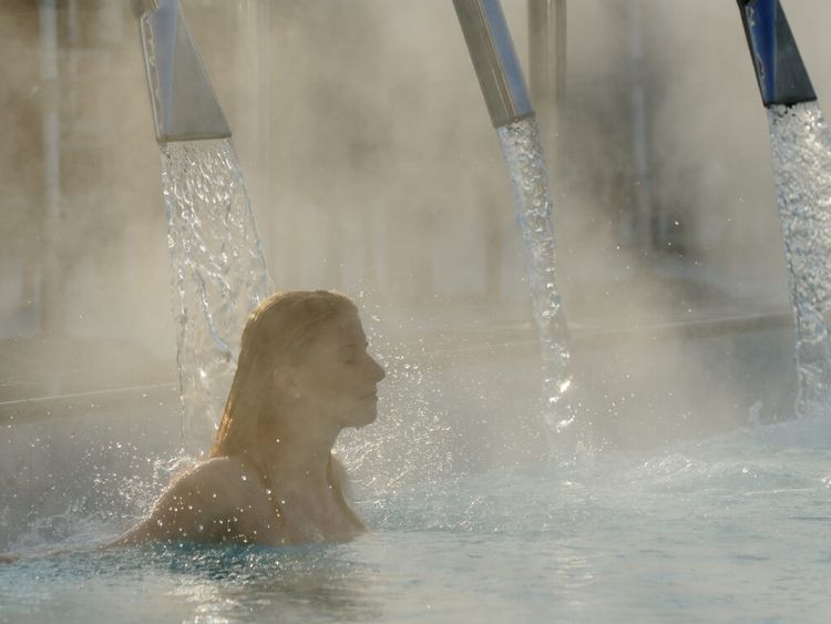 Junge Frau entspannt sich im Außenbecken eines Thermalbades